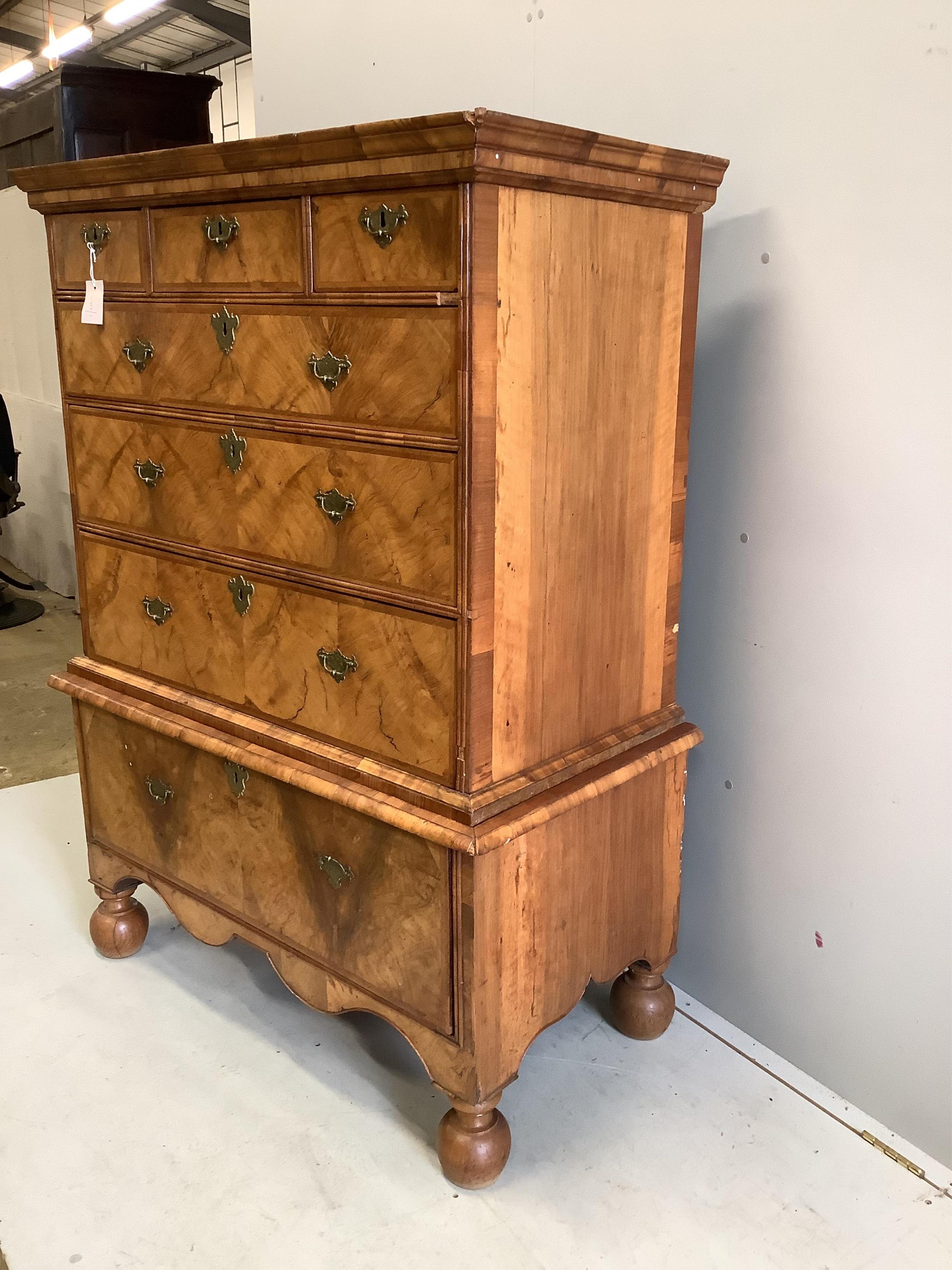 An early 18th century walnut chest on stand with later bun feet, width 106cm, height 147cm. Condition - fair